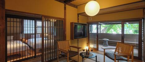 Une pièce de style japonais traditionnel, avec un sol recouvert de tatamis, des portes coulissantes et un téléviseur.