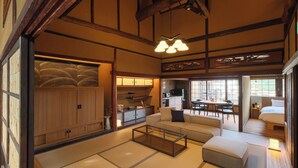 Une pièce de style japonais traditionnel, avec un sol recouvert de tatamis, une basse table en bois, un canapé et un lit.