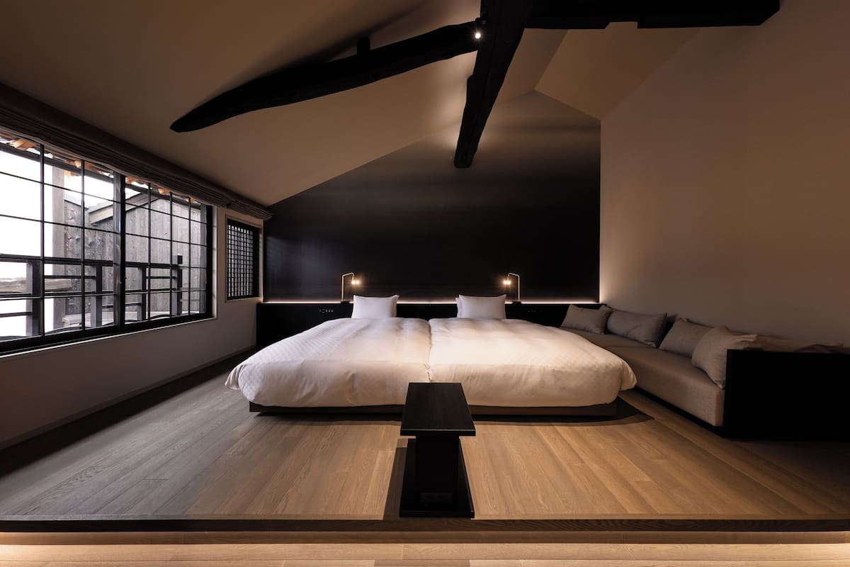 A modern bedroom with a large bed, a small table, and a sofa.