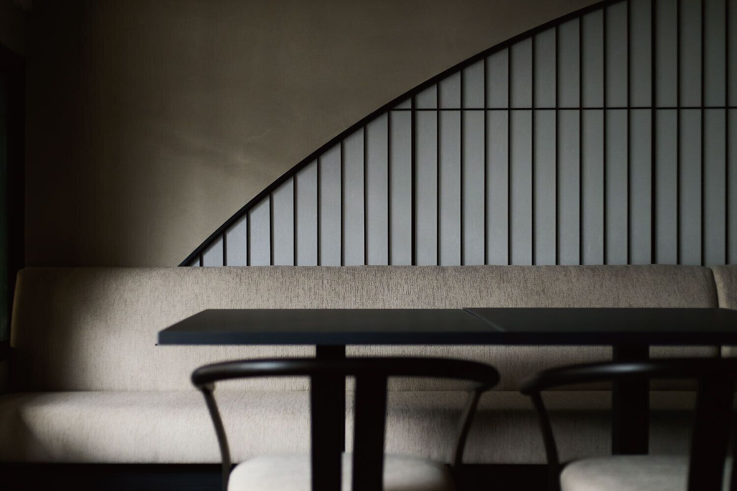 A modern interior with a curved wall, a sofa, and a table with chairs.
