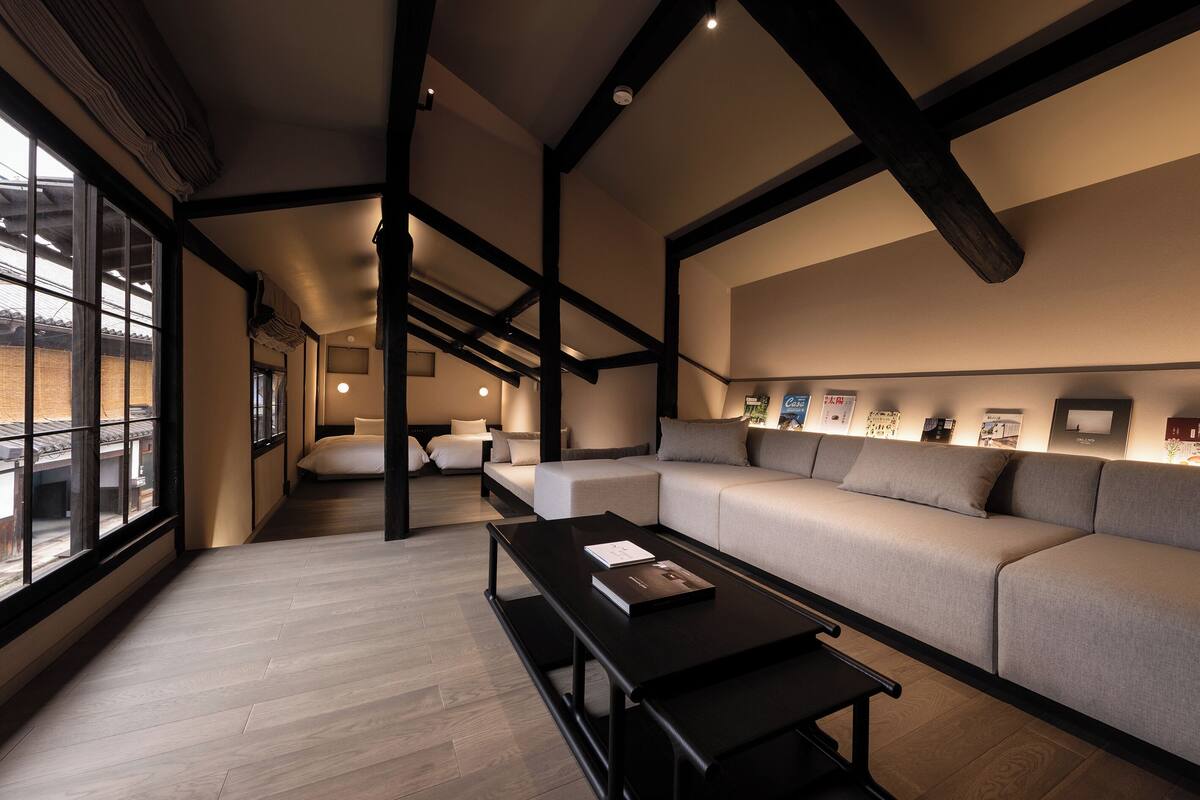 A modern interior with a sofa, a coffee table, and a view through large windows.