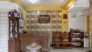 A cozy room with a wooden cabinet, a small round table with a plant, and a bookshelf filled with books and decorative items. - Coffee Swings Lodging House (Vigan)