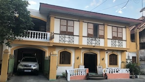 A two-story building with a yellow facade, a covered entrance, and a sign for 'COFFEESWINGS'. - Coffee Swings Lodging House (Vigan)