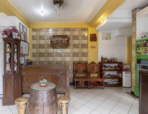 A cozy interior with a wooden reception desk, a coffee shop sign, and a small seating area with chairs and stools. - Coffee Swings Lodging House (Vigan)