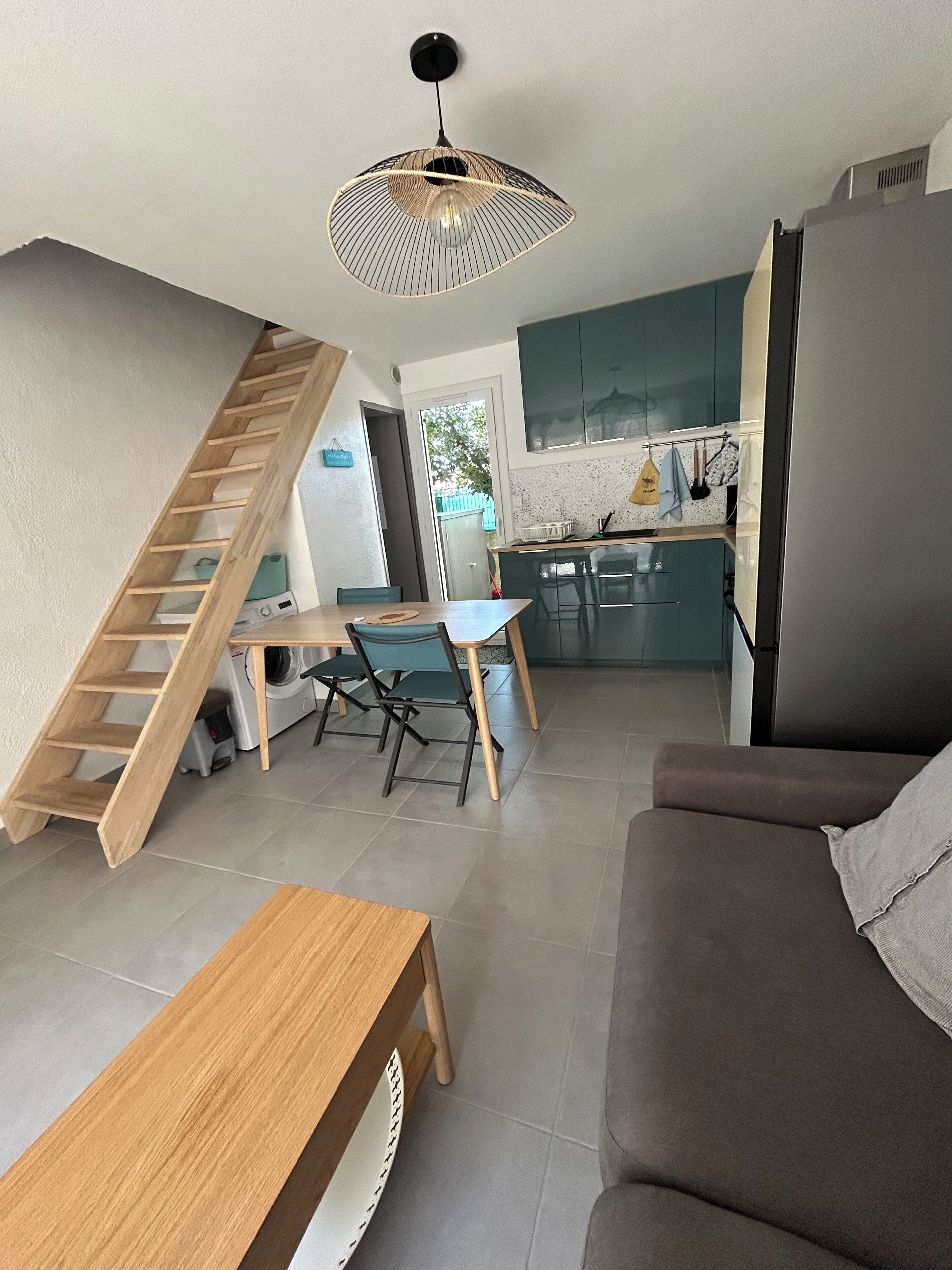 A modern living space with a staircase, a dining area, a kitchen, and a sofa.