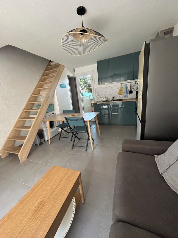 Et moderne opholdsrum med trappe, spiseplads, køkken og sofa.