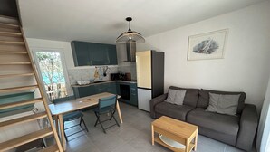 Ein kompakter Wohnbereich mit Küchenzeile, Essbereich und Sitzecke mit Sofa und Couchtisch.