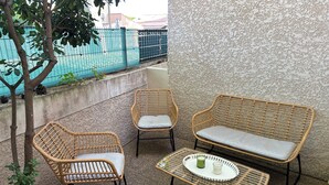 Ein kleiner Sitzbereich im Freien mit Korbmöbeln und einem Tisch.