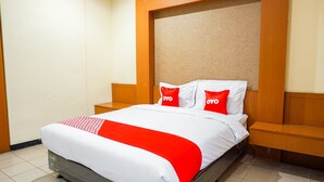 A hotel room with a bed, two nightstands, and a headboard with a textured panel.