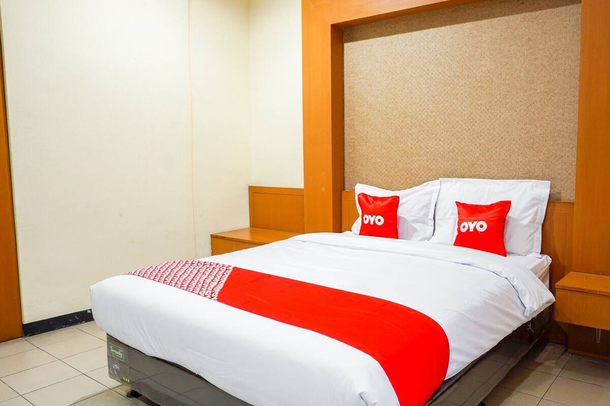 Ein Hotelzimmer mit einem Bett, zwei Nachttischen und einem Kopfteil mit einer strukturierten Oberfläche.