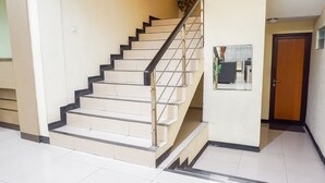 A staircase with a handrail, a door, and a wall-mounted object.