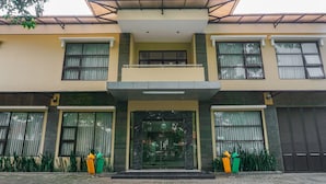 A two-story building with a central entrance, large windows, and a covered balcony.