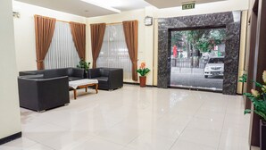 A reception area with a sofa, a small table, and a potted plant.