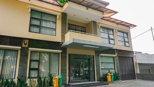 A two-story building with large windows, a balcony, and a gated entrance.