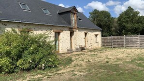 Une ferme en pierre avec un toit en pente et une clôture en bois en arrière-plan.