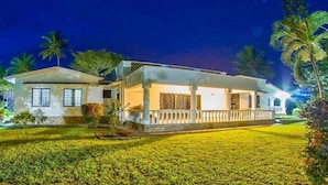 A two-story building with a balcony, surrounded by well-maintained lawns and palm trees. - Olive House (Mtwapa)