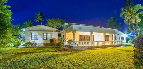 A two-story building with a balcony, surrounded by well-maintained lawns and palm trees. - Olive House (Mtwapa)