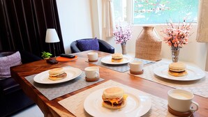A dining table set with sandwiches and coffee cups, surrounded by a sofa and decorative vases. - Downshifted House (Miaoli)