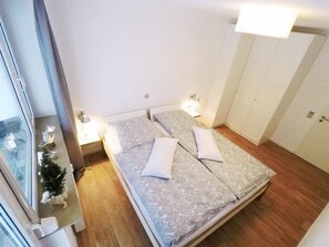 A bedroom with a bed, bedside lamps, a small Christmas tree, and a wardrobe. - FeWo Käppchen Winterberg (Winterberg)