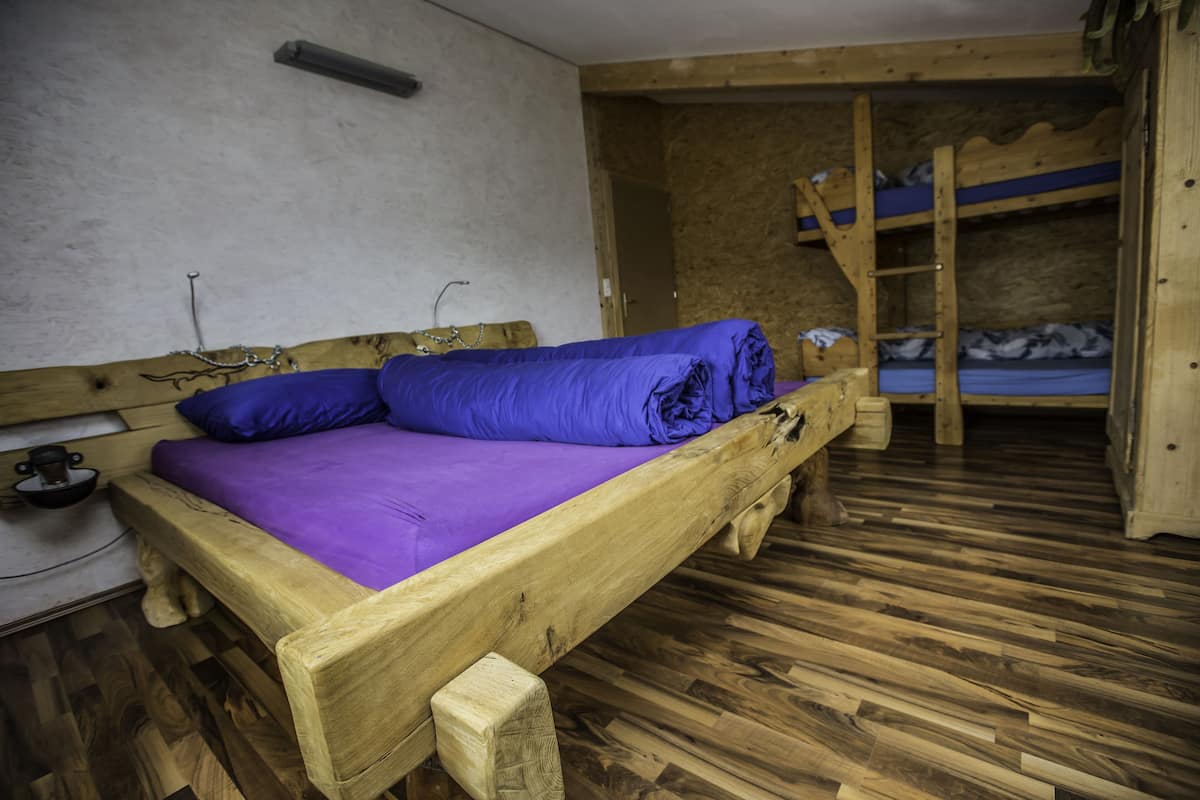A wooden bunk bed with a purple mattress in a rustic room with wooden flooring.