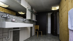 A modern bathroom with a large sink, wooden cabinets, and a chair. - Steigmatt Bauernhof - Erlebnis (Oberriet)