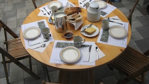 A round wooden table set for a meal with plates, cutlery, a jug, and a bread basket. - Steigmatt Bauernhof - Erlebnis (Oberriet)