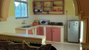 A compact kitchen with a window, a microwave, a refrigerator, and a sink. - Sadiana Apartments (Mtwapa)