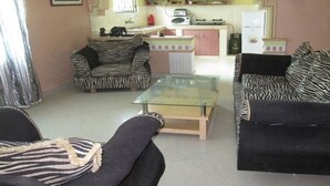 A living room with two zebra-patterned sofas, a glass coffee table, and a kitchen in the background. - Sadiana Apartments (Mtwapa)