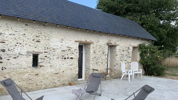 A stone building with a tiled roof, a small door, and a window. There are four lounge chairs and a table outside. - The Bahutière Annex and the Pineau (La chapelle sur oudon)
