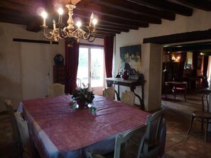 Une salle à manger avec une grande table, des chaises, un lustre et un tableau au mur.