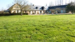 A large, open grassy field with a house in the background. - The Bahutière Annex and the Pineau (La chapelle sur oudon)