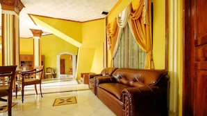 Amplia sala de estar con un sofá de cuero marrón, muebles de madera y paredes amarillas.