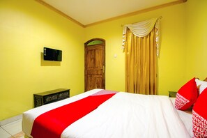 A room with a bed, a wooden door, a television on the wall, and a curtain. - OYO 1770 Hotel Mawar Saron 2 (Depok)