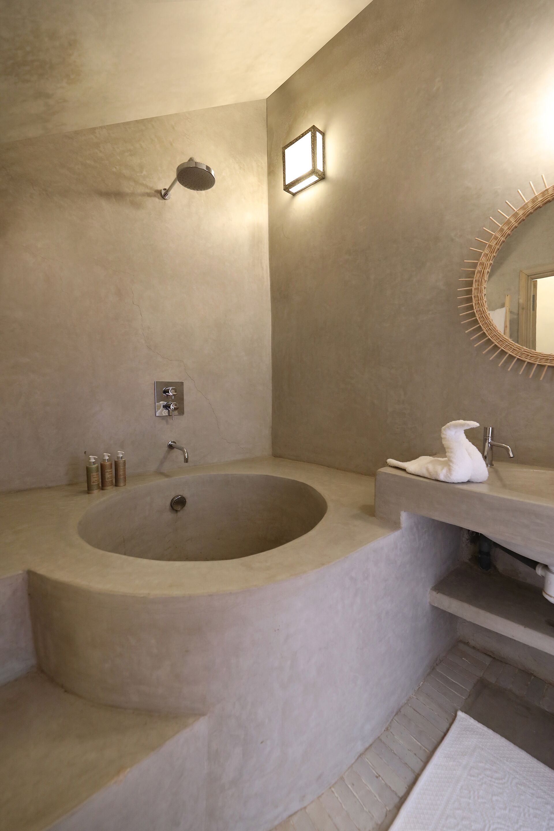 A bathroom with a large freestanding bathtub, a sink with a mirror, and a wall-mounted light fixture.
