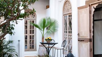 A courtyard with a table, chairs, a potted plant, and a decorative lantern.