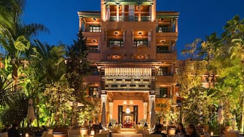 A multi-story hotel with a central courtyard, outdoor seating, and lush greenery.