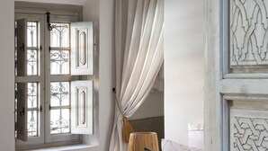 Un dormitorio con cama, ventana con cortinas, lámpara y puerta con molduras decorativas.