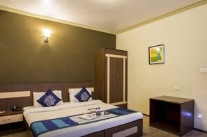 A hotel room with a bed, a wardrobe, a bedside table, and a small cabinet. - FabHotel The Junction (Gangtok)