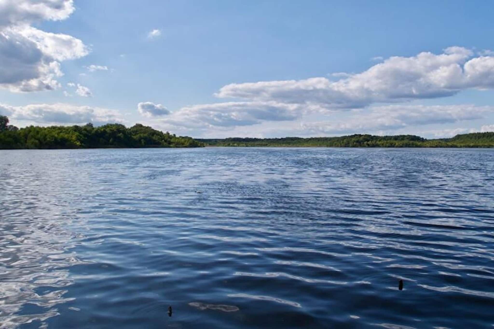 A calm lake with a forested shoreline and a clear sky.