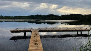 A wooden dock extending into a calm lake with a forested shoreline in the background.