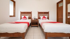 A double room with two beds, wooden headboards, a nightstand, and a mirror.