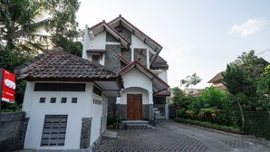 A two-story house with a tiled roof, a front porch, and a small attached garage.