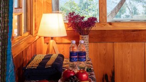 A wooden interior with a window, a table with a lamp, a book, and a bowl of fruit. - Zizi Homestay and Trekking - Hostel (Ta Van)