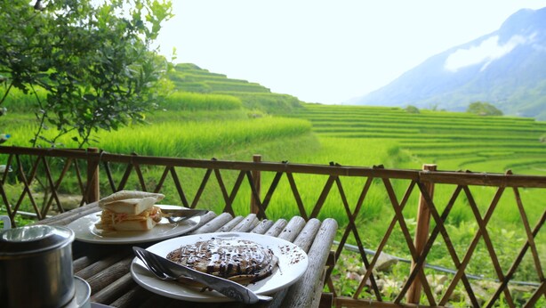A table with food and a scenic view of terraced fields and mountains. - Zizi Homestay and Trekking - Hostel (Ta Van)