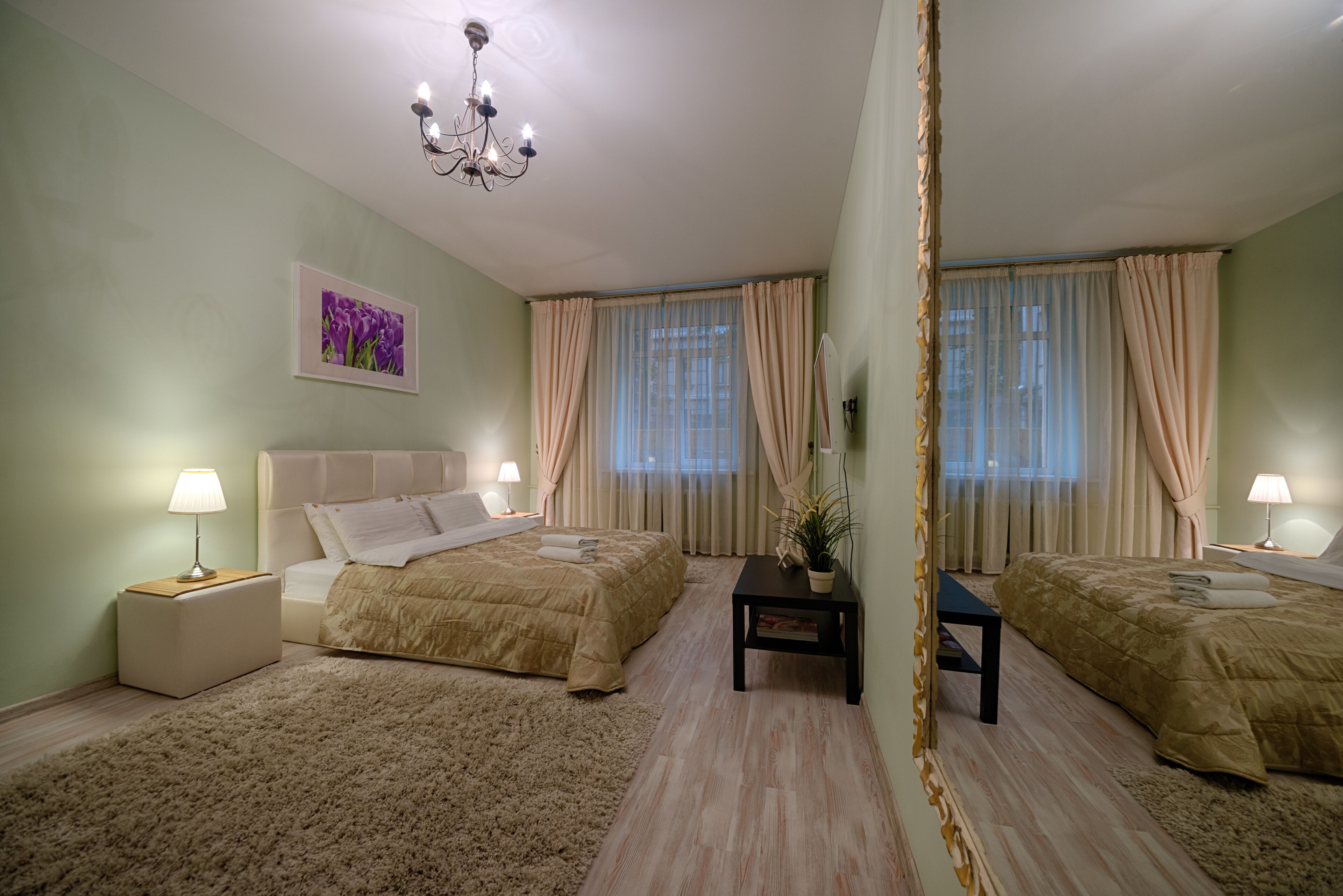 Ein Schlafzimmer mit zwei Betten, einem Nachttisch, einem Schminktisch und einer Chandelüster.