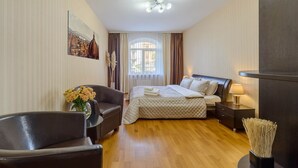 Una habitación de hotel con una cama, una silla, una mesita de noche, una lámpara y un cuadro en la pared.