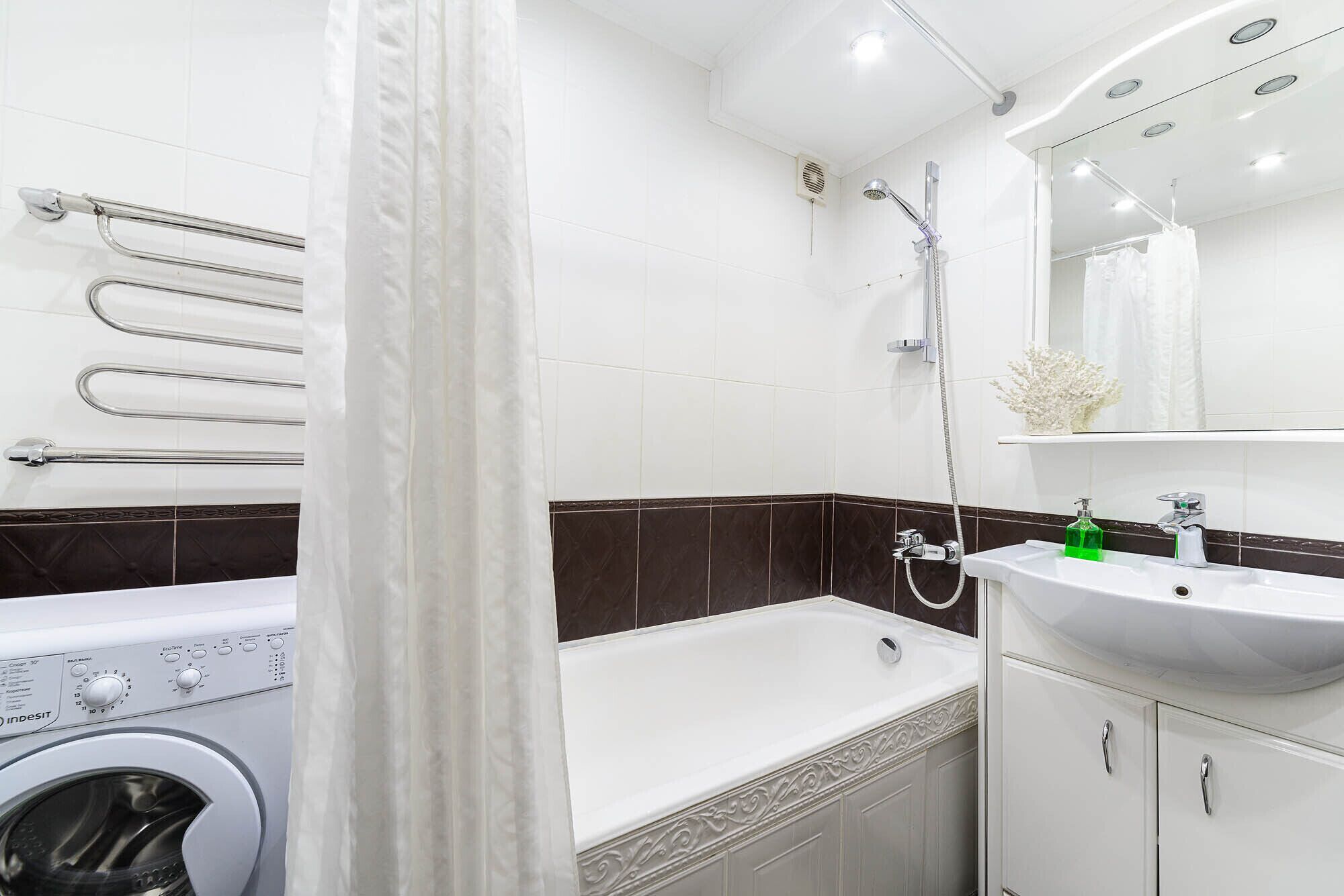 A modern bathroom with a washing machine, a bathtub, and a sink with a mirror above.