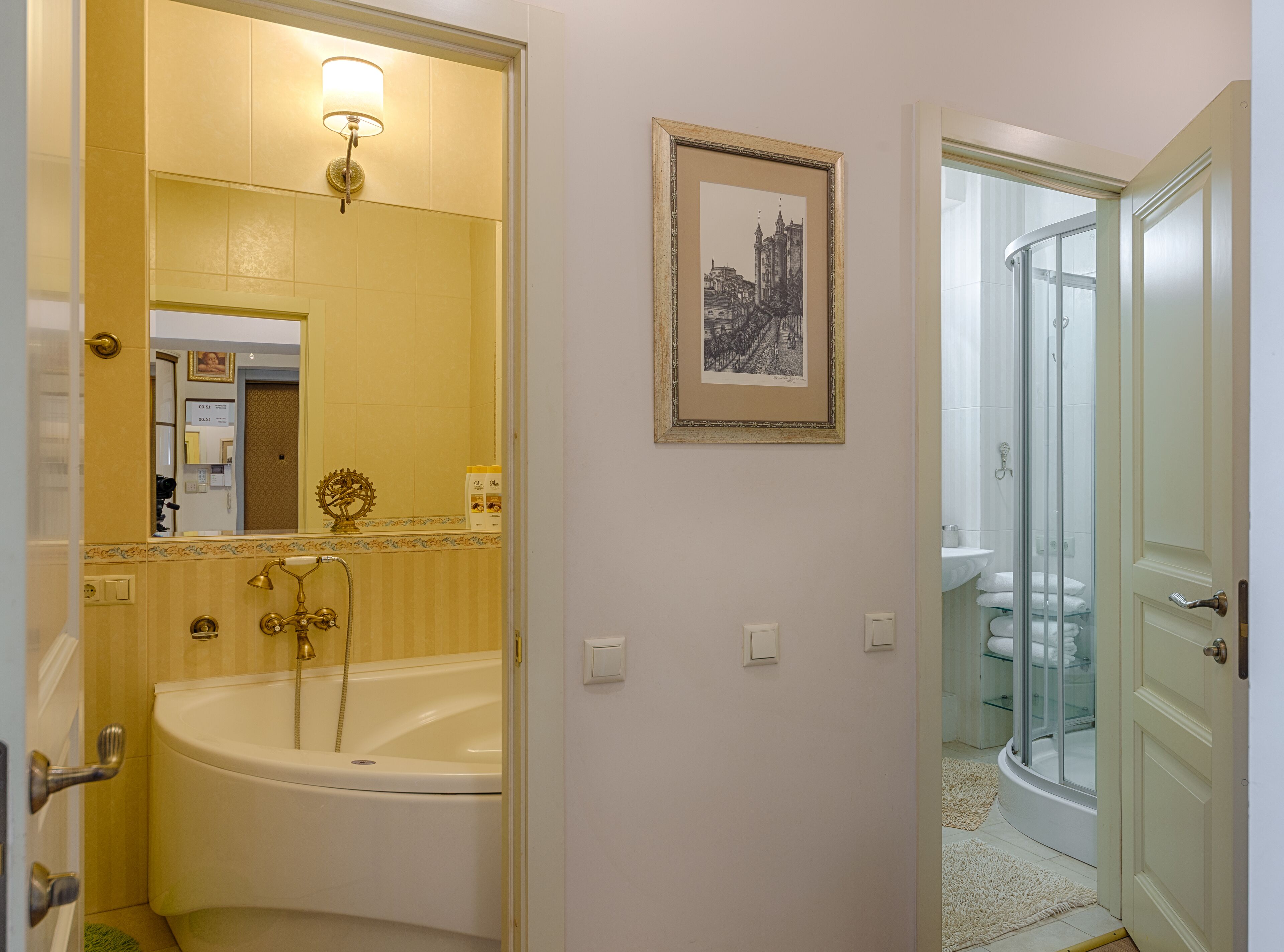 Une salle de bain équipée d’une baignoire, d’une douche et d’un espace de douche séparé par des parois en verre. Un tableau encadré est accroché au mur, et un miroir se trouve au-dessus de la baignoire.