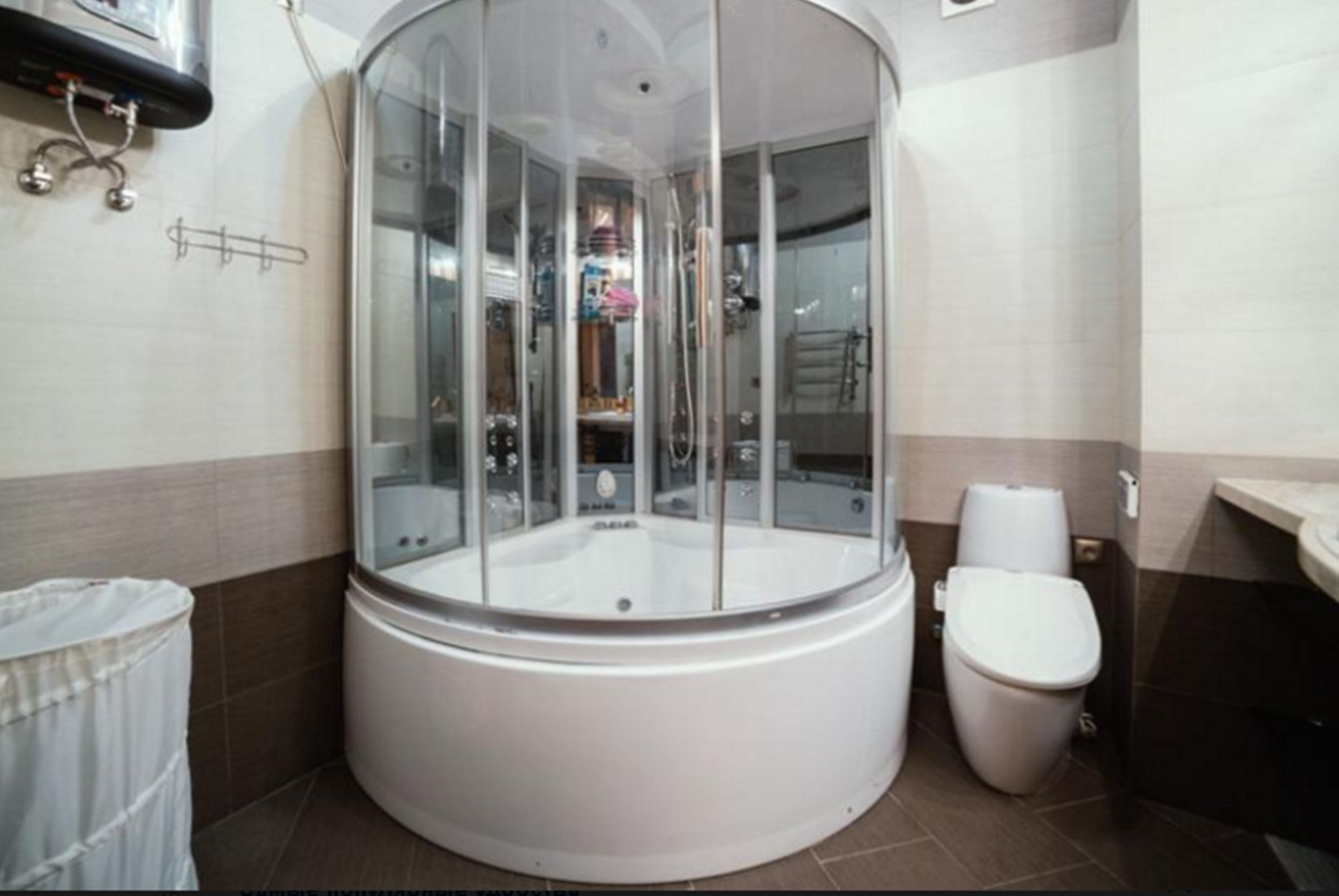 A modern bathroom with a glass-enclosed shower, a toilet, and a towel rack.
