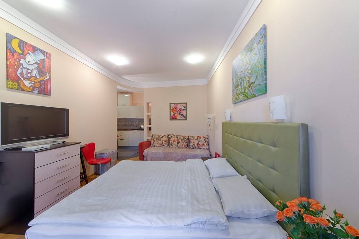 A bedroom with a bed, a TV, a desk, and a chair.